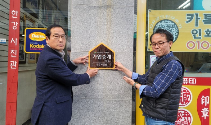 유준희 여주시 소상공인지원센터장(왼쪽)이 '가업승계' 지원사업 추진을 통해 선정된 업체에 '가업승계'인증 현판을 부착하고 있다. / 사진제공=여주시