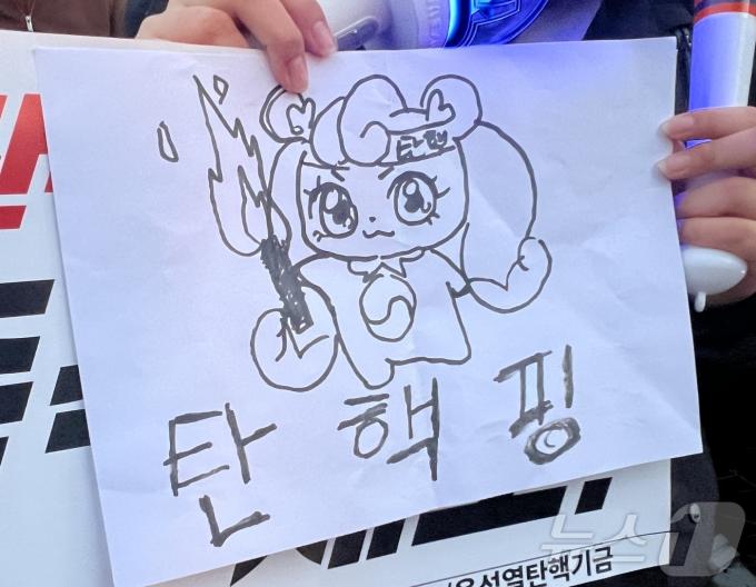8일 오후 서울 여의도 국회의사당역 인근에서 촛불행동의 주최로 열린 촛불문화제에 한 시민이 캐릭터 '하츄핑'을 패러디한 그림을 들고 참가하고 있다. 2024.12.08/뉴스1 ⓒ News1 김민수 기자