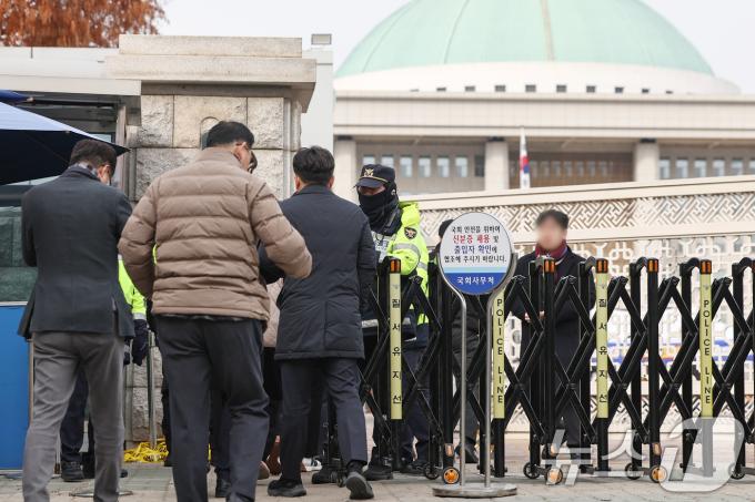 13일 서울 영등포구 여의도 국회의사당 앞에서 경찰이 방문자들에게 출입증을 확인하고 있다. 국회가 윤석열 대통령 탄핵소추안이 국회에 보고되는 이날부터 표결이 예정된 14일까지 국회 출입을 전면 제한한다. 국회 사무처는 