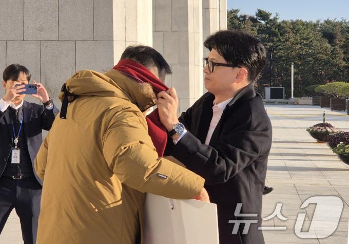 한동훈 국민의힘 대표가 14일 오전 서울 여의도 국회에서 출근하며 윤석열 대통령 탄핵 찬성 1인 시위 중인 김상욱 의원에게 자신의 목도리를 둘러주고 있다. (김상욱 의원실 제공) 2024.12.14/뉴스1
