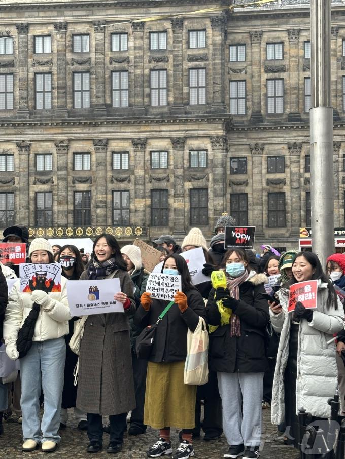 14일(현지시간) 네덜란드 암스테르담 담 스퀘어에서 교민과 유학생들이 응원봉과 재치 있는 문구로 윤석열 대통령 탄핵을 촉구하고 있다. '감튀+마요네즈 국룰 협회'에서도 참석했다. 2024.12.14/ⓒ 뉴스1 차현정 통신원