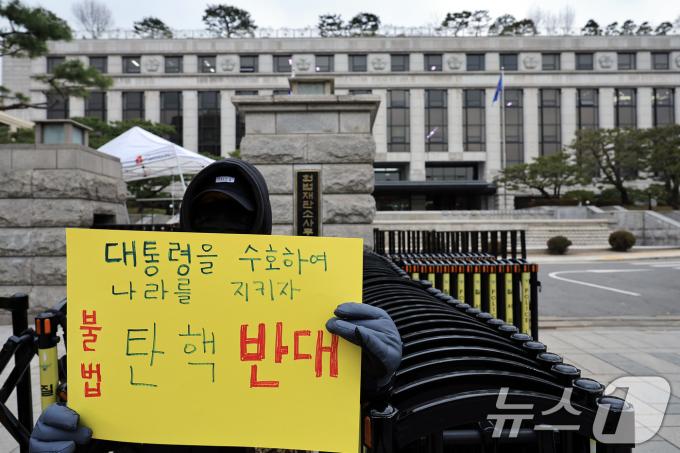 윤석열 대통령에 대한 본격적인 탄핵심판절차에 돌입한 16일 오후 서울 종로구 재동 헌법재판소 앞에서 '대통령을 수호하여 나라를 지키자, 불법 탄핵 반대' 손피켓을 든 시민이 탄핵 반대 1인 시위를 하고 있다. 2024.12.16/뉴스1 ⓒ News1 박정호 기자
