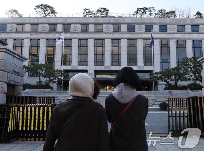 윤석열 대통령 탄핵소추안이 국회에서 가결되면서 공이 헌법재판소로 넘어왔다. 탄핵 사건이 접수되면 헌법재판소는 180일 내에 대통령 파면 여부를 결정해야 한다. 15일 서울 종로구 헌법재판소 앞에서 시민들이 헌재를 바라보고 있다. 2024.12.15/뉴스1 ⓒ News1 송원영 기자