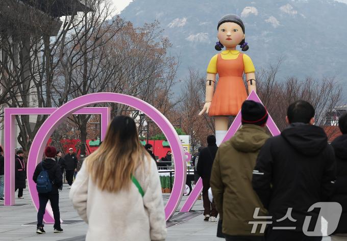 성탄절인 25일 서울 종로구 광화문광장에 설치된 넷플릭스 오리지널시리즈 '오징어게임2'의 '영희'의 대형 모형 앞으로 시민들이 지나고 있다. 한편, '오징어 게임 시즌2'는 ‘K-콘텐츠’의 신기록을 쓴 ‘오징어 게임’의 후속작으로 26일 전 세계에 공개된다. 2024.12.25/뉴스1 ⓒ News1 김진환 기자