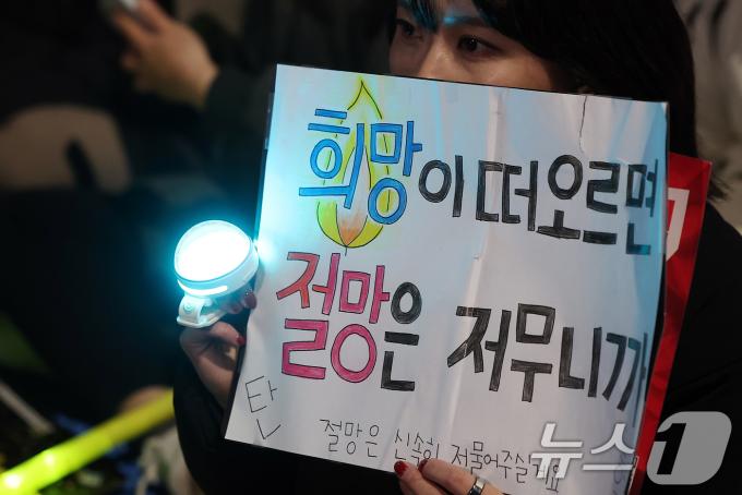 윤석열 대통령에 대한 국회의 2차 탄핵소추안 표결을 하루 앞둔 13일 오후 서울 영등포구 여의도 국회 앞에서 열린 '윤석열 즉각 탄핵 구속 촉구 촛불문화제'에서 참가자가 응원봉과 손피켓을 들어 보이고 있다. 2024.12.13/뉴스1 ⓒ News1 김진환 기자