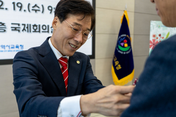 최윤홍 부산시교육감 권한대행이 19일 지방공무원 발령을 받은 공무원에게 배지를 달아주고 있다./사진=부산시교육청