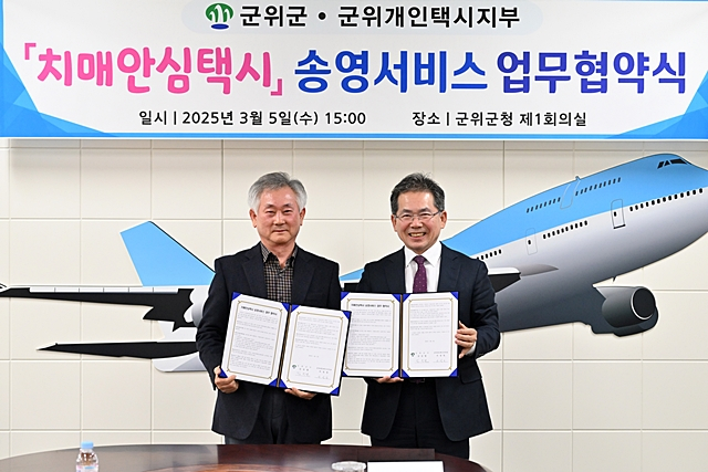 왼쪽부터 서성일 군위개인택시지부장과 김진열 군위군수가 업무협약서를 들어보이고 있다./사진제공=대구 군위군