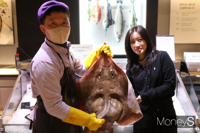 롯데백화점 광주점 지하1층 식품행사장 직원들이 오는 17일까지 진행하는 홍어 대축제 기간을 맞아 '흑산도산 홍어'를 들어보이고 있다/사진=롯데백화점 홍보 3팀 제공.