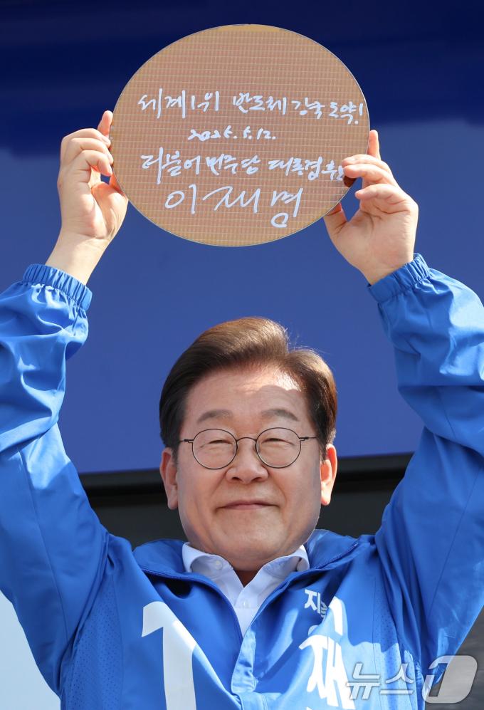 이재명 더불어민주당 대통령 후보가 제21대 대통령 선거 공식 선거운동 첫날인 12일 오후 경기 화성시 동탄 센트럴파크 음악분수중앙광장에서 '세계1위! 반도체 강국도약!'이라고 쓴 반도체 웨이퍼를 들어 보이고 있다. (공동취재) 2025.5.12/뉴스1 ⓒ News1 안은나 기자