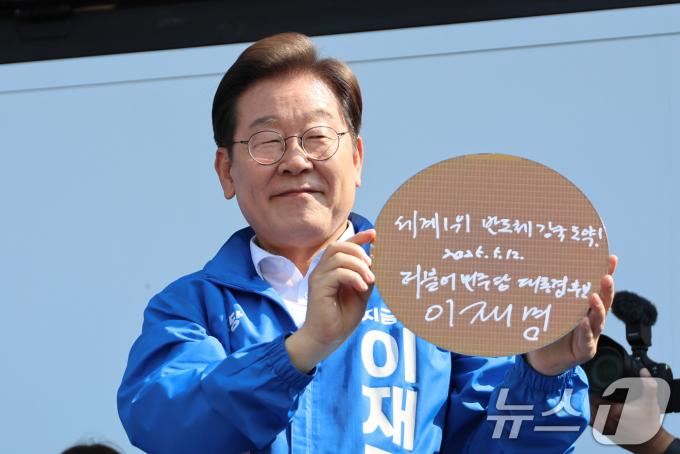 이재명 더불어민주당 대통령 후보가 제21대 대통령 선거 공식 선거운동 첫날인 12일 오후 경기 화성시 동탄 센트럴파크 음악분수중앙광장에서 '세계1위! 반도체 강국도약!'이라고 쓴 반도체 웨이퍼를 들어 보이고 있다. (공동취재) 2025.5.12/뉴스1 ⓒ News1 안은나 기자