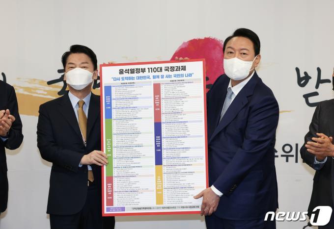 윤석열 대통령 당선인이 3일 오전 서울 종로구 삼청동 인수위원회 대회의실에서 열린 '제8차 인수위원회 전체회의'에서 안철수 인수위원장에게 '윤석열 정부 110대 국정과제'를 전달 받은 후 기념 촬영을 하고 있다. 2022.5.3/뉴스1 ⓒ News1 인수위사진기자단