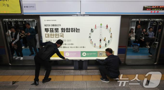 제21대 대통령선거를 20일 앞둔 14일 오전 서울 종로구 지하철 혜화역 승강장 스크린도어에 선관위 관계자들이 대선 홍보물 래핑작업을 하고 있다. 2025.5.14/뉴스1 ⓒ News1 박세연 기자