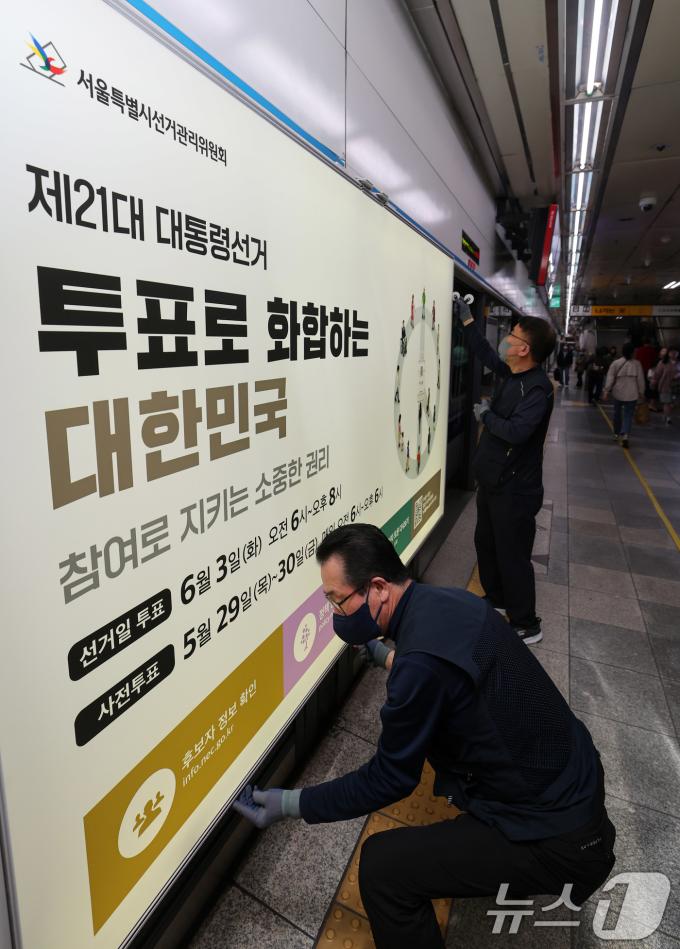 제21대 대통령선거를 20일 앞둔 14일 오전 서울 종로구 지하철 혜화역 승강장 스크린도어에 선관위 관계자들이 대선 홍보물 래핑작업을 하고 있다. 2025.5.14/뉴스1 ⓒ News1 박세연 기자