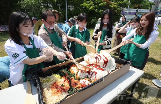 139주년 대동제가 열리는 14일 서울 서대문구 대현동 이화여자대학교 잔디광장에서 총학생회 임원들과 교직원들이 학생들에게 나눠줄 대형 비빔밥을 비비고 있다. 2025.5.14/뉴스1 ⓒ News1 김진환 기자