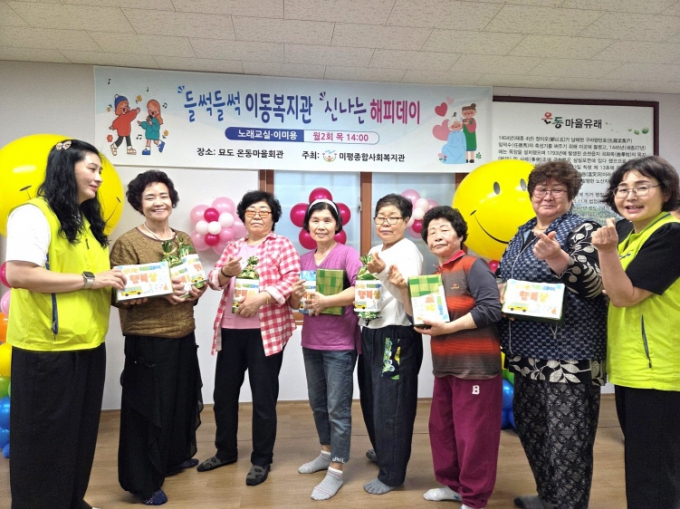 여수 미평종합사회복지관은 15일 묘도 온동·도독마을에서 이동복지관 '신나는 해피데이'를 운영하고 주민들과 기념촬영하고 있다./사진=미평종합사회복지관