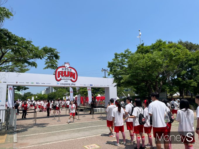 지난 25일 ‘무한도전 Run with 쿠팡플레이’ 행사에서 참가자들이 서울 영등포구 여의도공원 입구 앞에서 줄을 서 입장하고 있으며, 일부는 무한도전 로고 앞에서 인증샷을 남기고 있다. /사진=김대영 기자