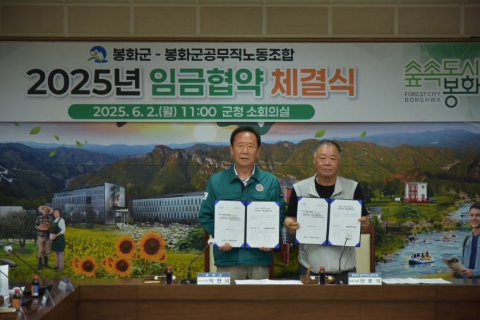 박현국 봉화군수(왼쪽)와 전종국 봉화군공무직노조위원장(오른쪽)이 임금협약 체결식을 가진 뒤 협약서를 들어보이고 있다./사진제공=경북 봉화군