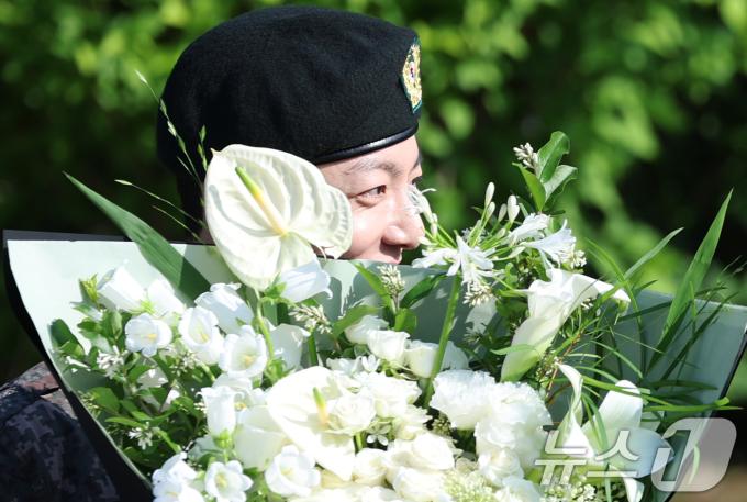 방탄소년단(BTS)의 정국이 11일 오전 경기도 연천군 연천공설운동장에서 군복무를 마친 뒤 꽃다발을 받고 수줍은 미소를 짓고 있다. ⓒ News1 권현진 기자