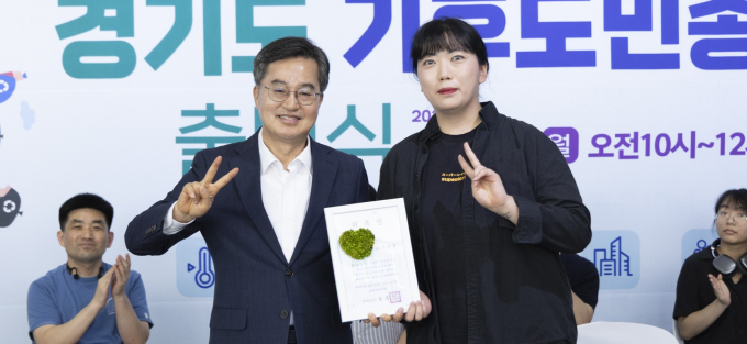 김동연 경기도지사(왼쪽)가 기후도민총회 회원에게 재생용지를 사용한 용지에 이끼를 심은 친환경 위촉장 수여하고 있다.  