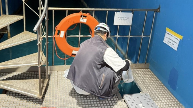 도시군 합동점검반원이 최종방류구에서 채수하고 있는 모습. /사진제공=경기도