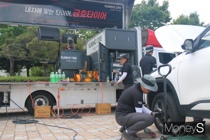 금호타이어 직원들이 광주광역시청 야외음악당에 마련된 '타이어 무상점검' 캠페인에서 방문객의 차량을 점검하고 있다/사진=금호타이어 제공.