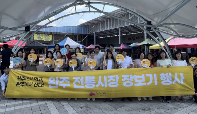 전주시청 공무원들이 완주군 삼례시장을 찾아 장보기 행사 등을 마치고 완주·전주 행정통합을 위한 화이팅을 외치고 있다./사진=전주시