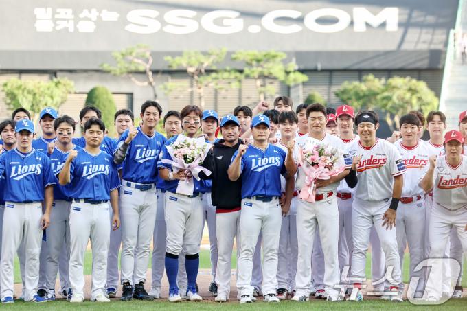 전격 은퇴를 선언한 삼성 오승환이 7일 오후 인천 미추홀구 SSG랜더스필드에서 열린 은퇴 기념행사에서 SSG 김광현으로부터 꽃다발을 선물 받은 뒤 양팀 선수들과 함께 기념촬영을 하고 있다. 2025.8.7/뉴스1 ⓒ News1 민경석 기자