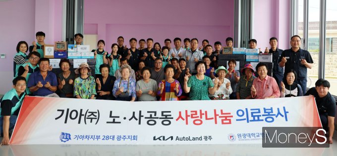 문재웅 기아 오토랜드광주 공장장, 은용철 기아노조 광주지회장,원광대병원 의료봉사단원들이 의료봉사를 마친 후 주민들과 기념사진을 찍고 있다/사진=기아 오토랜드광주 제공.  