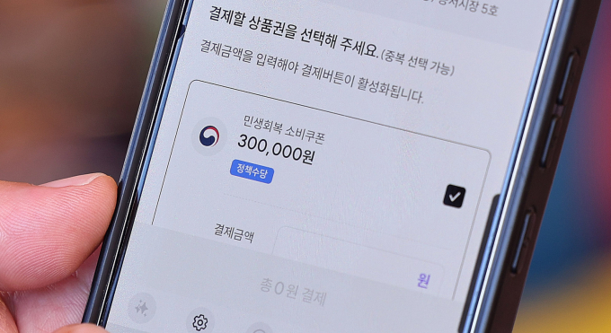 민생회복 소비쿠폰 1차 지급이 신청 시작 18일 만에 신청률 95.2%를 기록하며 사실상 마무리 단계에 접어들었다. 사진은 지난달 27일  서울 동대문구 청량리종합시장을 찾은 한 시민이 민생회복 소비쿠폰을 사용하는 시민. /사진=뉴스1