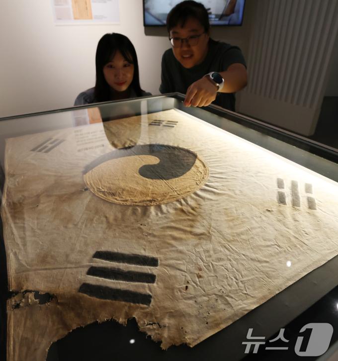 11일 오전 서울 중구 덕수궁 돈덕전에서 열린 '빛을 담은 항일유산' 특별전 언론공개회에서 방문객들이 일제강점기 당시 일장기를 먹으로 덧칠해 만든 '서울 진관사 태극기'를 살펴보고 있다. 국가유산청이 광복 80주년을 맞아 개항기부터 대한제국, 일제강점기, 광복에 이르는 시대를 110여 점의 유물을 소개하는 이번 전시는 오는 12일부터 두 달간 개최된다. 2025.8.11/뉴스1 ⓒ News1 오대일 기자