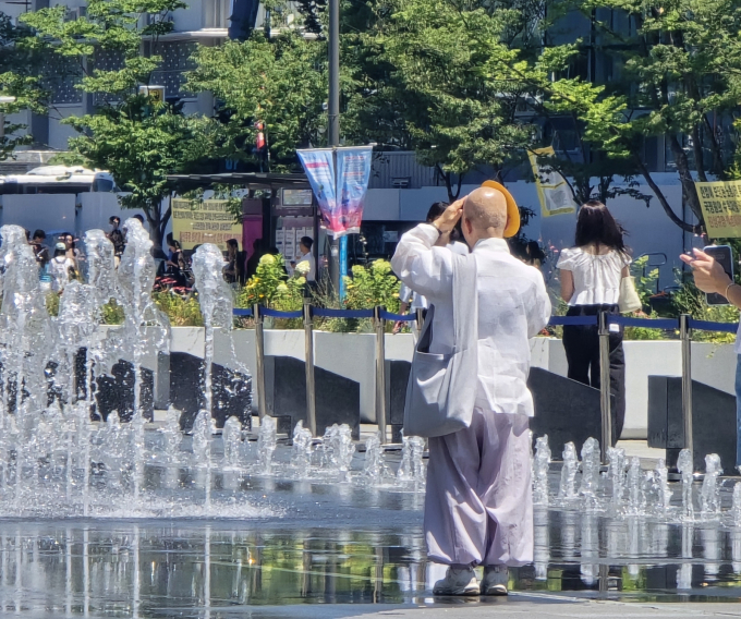 태국의 한 사원에서 4회 연속 복권 당첨 번호를 맞힌 '성수 그릇'이 화제다. 사진은 지난 7월 폭염 특보가 이어지는 서울 광화문에서 한 스님이 부채로 햇볕을 가리고 분수대를 바라보고 있는 모습. /사진=뉴스1