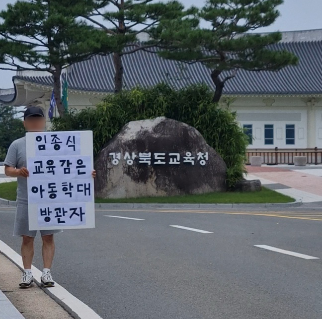 상주 씨름부 아동학대 피해학생의 부모가 18일 경북도교육청 앞에서 '임종식 교육감은 아동학대 방관자'라는 피켓을 들고 교육청의 책임 있는 조사를 촉구하며 1인 시위를 벌이고 있다./사진제공=머니S 독자제공