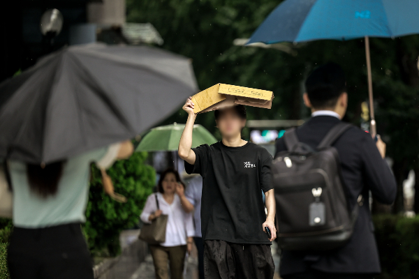 오는 19일은 전국이 흐리고 곳곳에 소나기가 내리겠다. 사진은 소나기가 쏟아진 지난 8일 서울 중구 청계천 일대에서 한 시민이 박스로 머리를 가린 채 이동하고 있는 모습. /사진=뉴시스