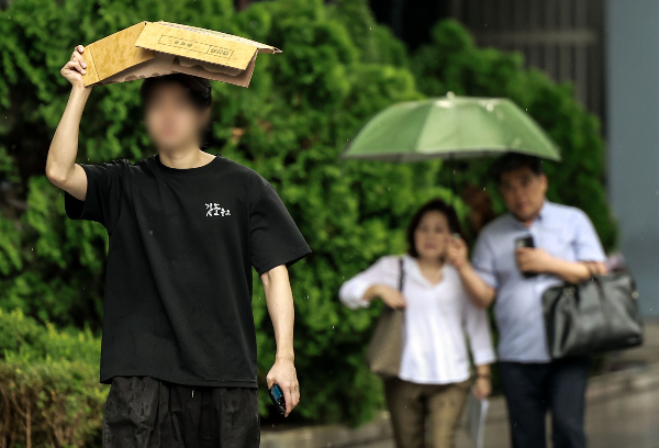 오는 22일은 전국이 대체로 흐리고 무덥겠다. 사진은 소나기가 쏟아진 지난 8일 서울 중구 청계천 일대에서 한 시민이 박스로 머리를 가린 채 이동하고 있는 모습. /사진=뉴시스