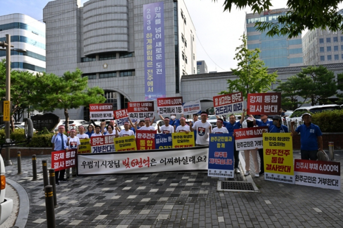  완주군의회 의원 11명 전원과 통합 반대 단체 회원 등 40여 명이 20일 오전 전주시청 앞에서 완주·전주 통합 결사반대 등의 구호가 적힌 피켓과 현수막을 들고 출근길 캠페인을 하고 있다./사진=완주군