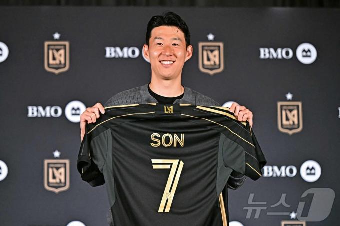 손흥민이 6일(현지시간) 로스앤젤레스 BMO 스타디움 필드 클럽에서 열린 로스앤젤레스 FC(LAFC) 입단 기자회견에서 7번 유니폼을 들고 미소를 보이고 있다. 구단에 따르면 계약 기간은 2027년까지이며, 옵션에 따라 2029년까지 연장할 수 있다. ⓒ AFP=뉴스1