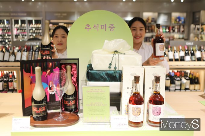롯데백화점 광주점 지하1층 와인매장 직원들이 '아트 콜라보레이션 주류 선물세트'를 선보이고 있다/사진=롯데백화점 홍보3팀 제공.