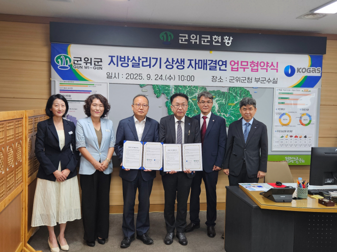 군위군 관계자와 가스공사 관계자가 협약식에서 업무협약서를 들어보이고 있다. /사진제공=군위군