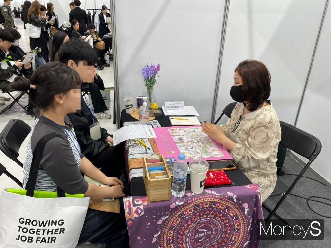 21일 서울 강서구 코엑스 마곡 컨벤션센터에서 열린 '2025 상생협력 채용박람회'에 마련된 '취업타로' 부스에서 한 청년 구직자가 타로 상담사로부터 취업운세와 관련한 설명을 듣고 있다. / 사진=이한듬 기자