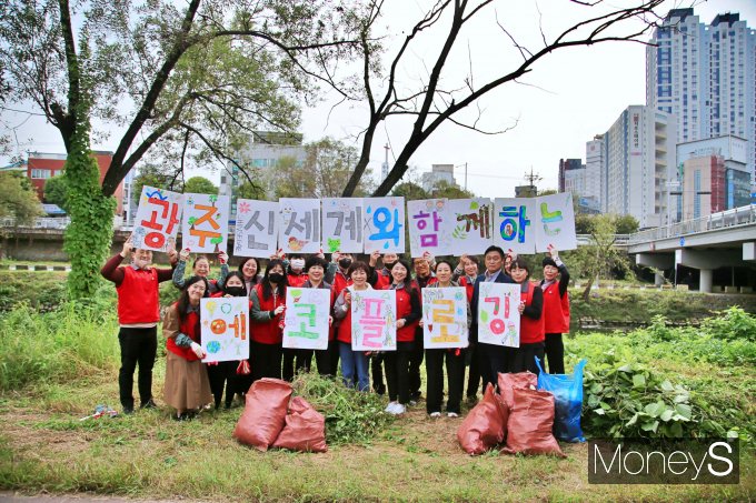 광주신세계 임직원 봉사단과 광주환경운동연합 회원들은 지난 21일 광주천변에서 에코 플로깅과 유해식물 제거 활동을 펼친 후 기념사진을 찍고 있다/사진=광주신세계 제공.