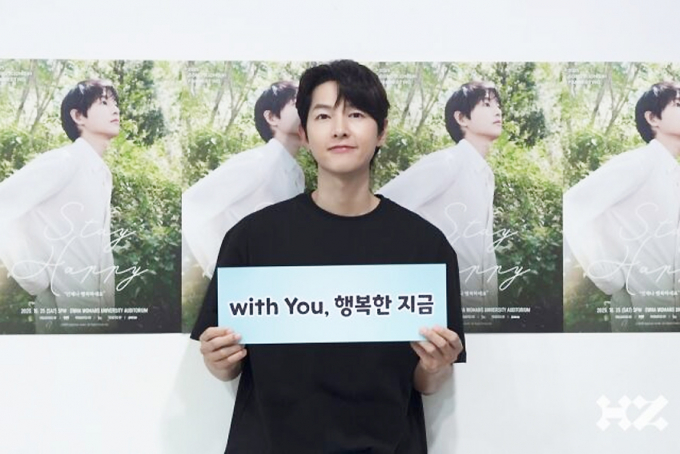 배우 송중기가 지난 25일 국내 팬미팅 '스테이 해피'를 성황리에 마쳤다. 사진은 팬미팅 현장에서 송중기가 위드 유, 행복한 지금 글귀가 적힌 카드를 들고 포즈를 취하고 있는 모습. /사진=하이지음스튜디오 제공
