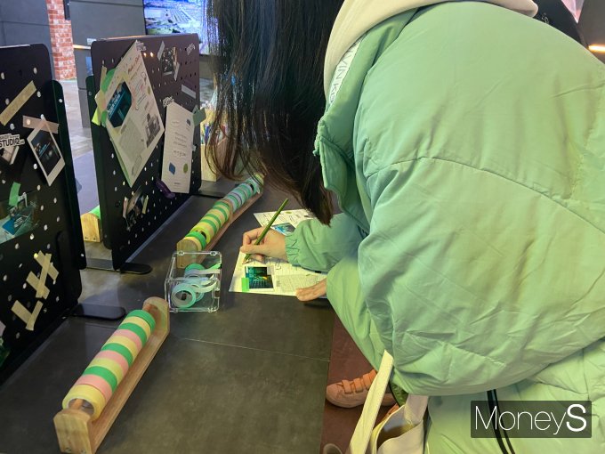 자유로 기공식을 배경으로 한 사진은 즉석 인화가 가능하다. 사진은 인화한 사진을 엽서에 붙이고 꾸미는 방문객의 모습. /사진=최성원 기자