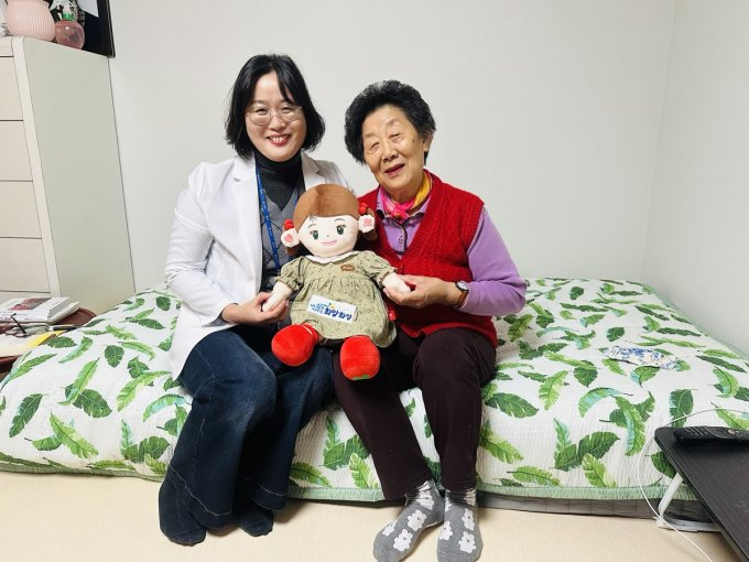 화성시동탄보건소 관계자와 독거 어르신이 AI 돌봄로봇 '효돌이'를 함께 들고 환하게 웃고 있다. /사진제공=화성특례시