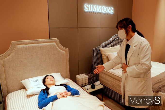 광주신세계 본관 8층 시몬스 매장에서 고객이 윌리엄 매트리스를 체험하며 직원 설명을 듣고 있다/사진=광주신세계 제공.