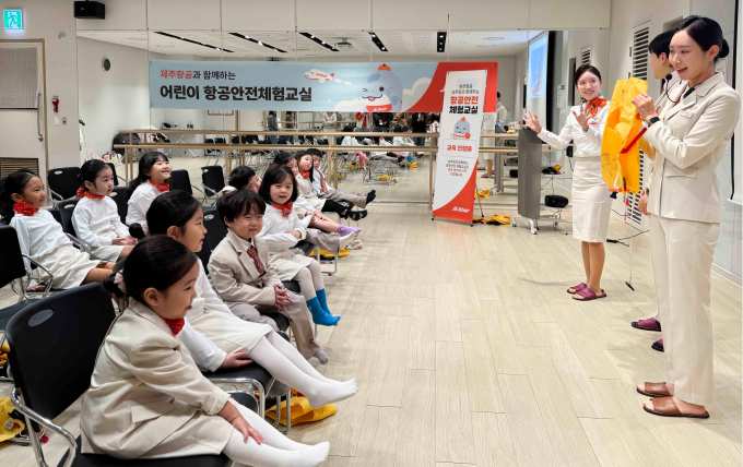 제주항공 객실승무원들이 지난 16일 스타필드마켓 일산점에서 진행된 ‘제주항공과 함께하는 어린이 항공안전체험교실’에서 어린이에게 비상상황 발생시 구명조끼를 착용하는 방법을 가르쳐 주고 있다. /사진=제주항공