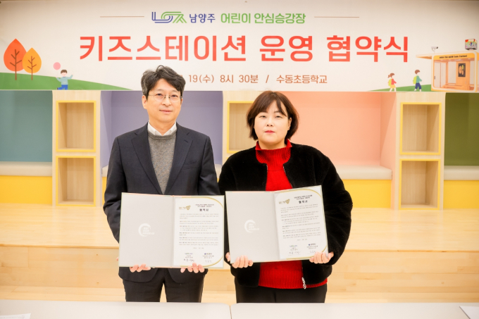  홍지선 남양주시 부시장(왼쪽)이 19일 수동초등학교에서 곽유선 수동초 학부모회장과 어린이 안심승강장 '키즈스테이션' 운영 협약 체결하고 협약서를 들고 사진촬영을 하고 있다. /사진제공=남양주시 